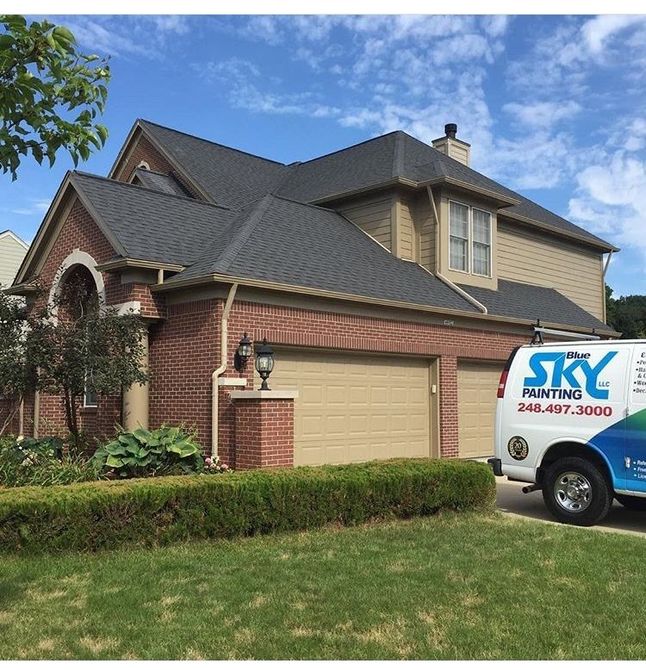 A sky painting truck is parked in front of a house