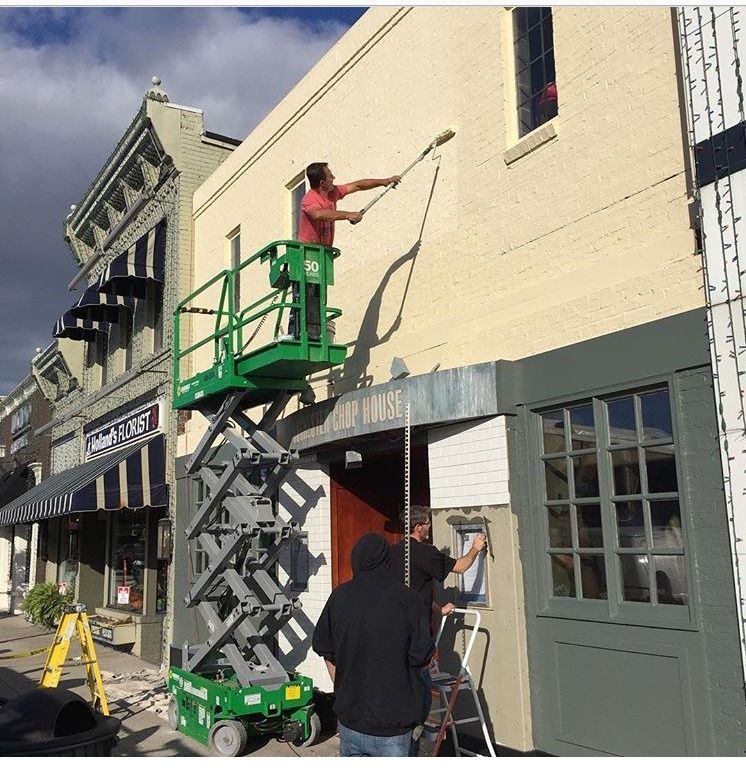 A man paints the side of a building with a roller