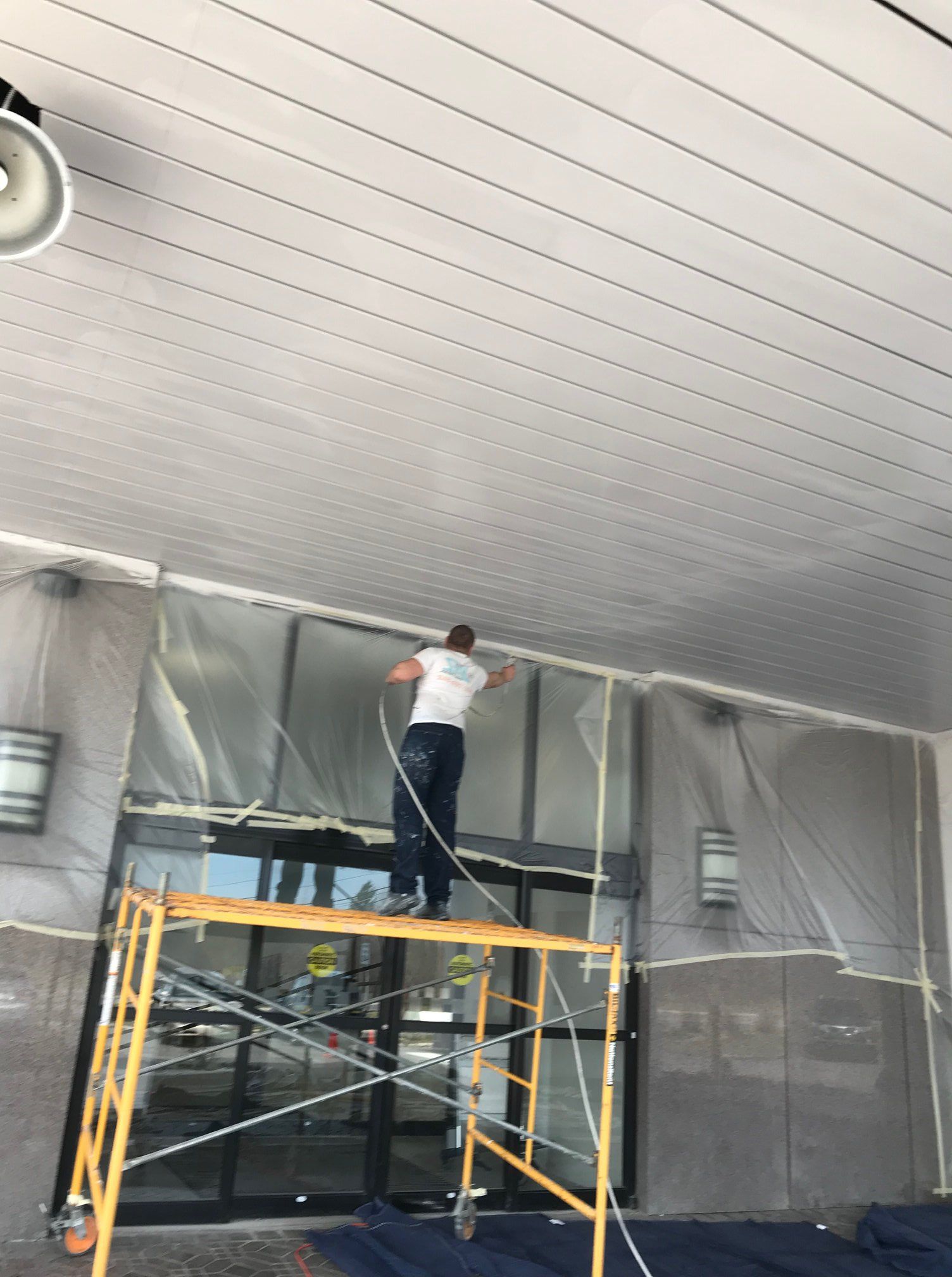 A man is standing on a scaffolding painting the ceiling of a building