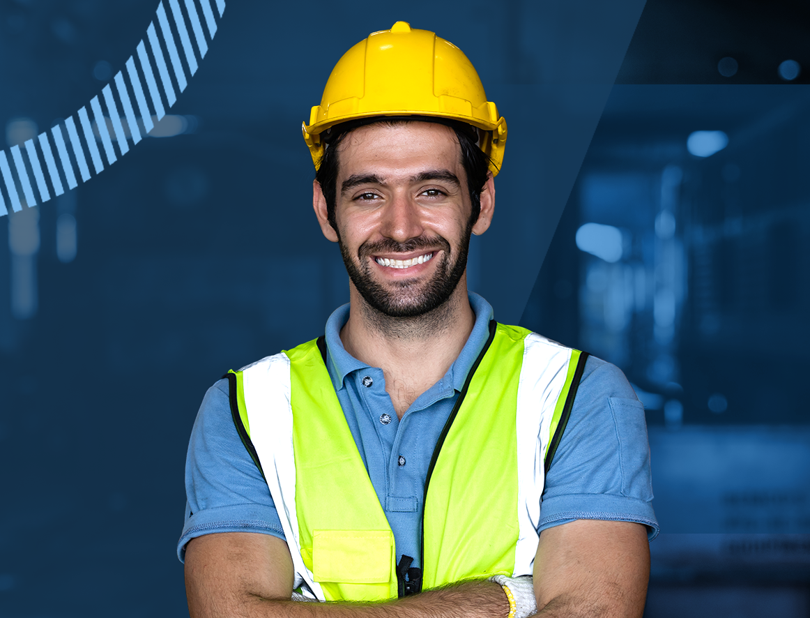 A man wearing a hard hat and safety vest is smiling with his arms crossed.