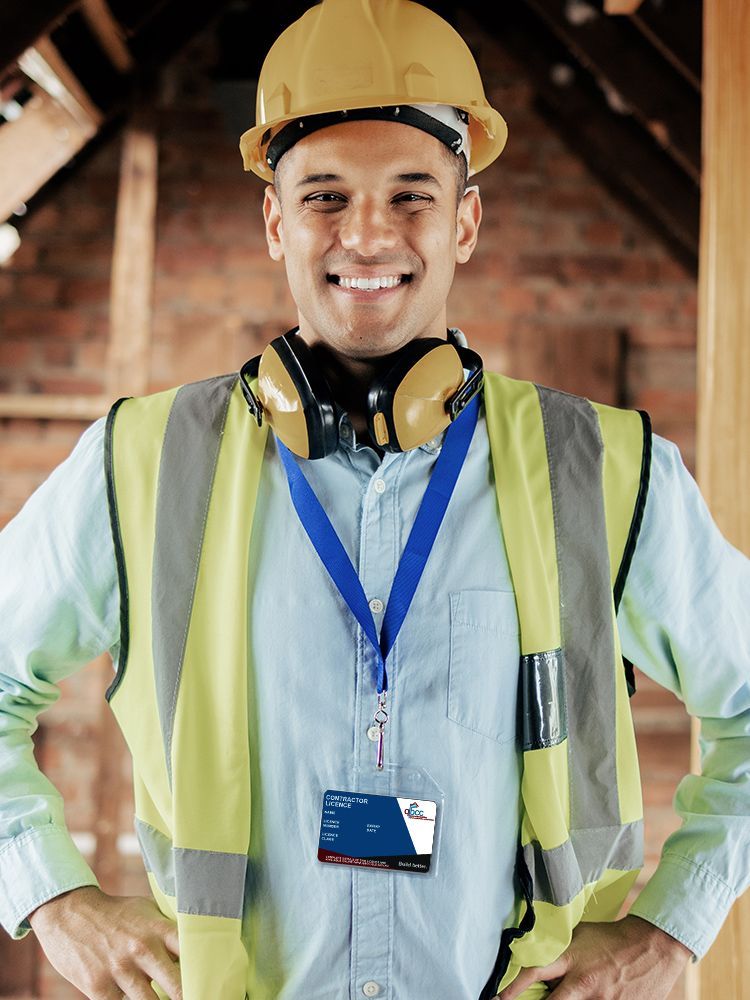 A man wearing a hard hat and safety vest is standing with his hands on his hips.