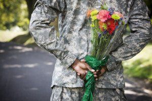 man in uniform holds flowers behind his back