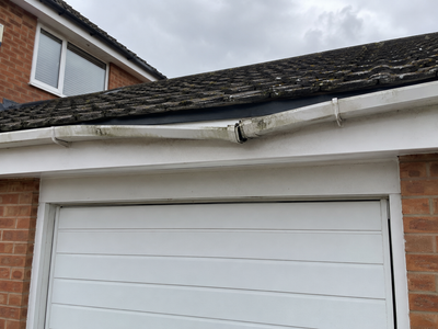 Sagging white gutter over a garage before repair
