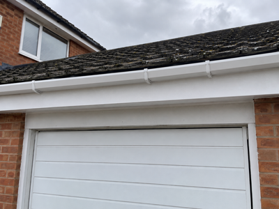 White gutter over a garage straight and level after repair