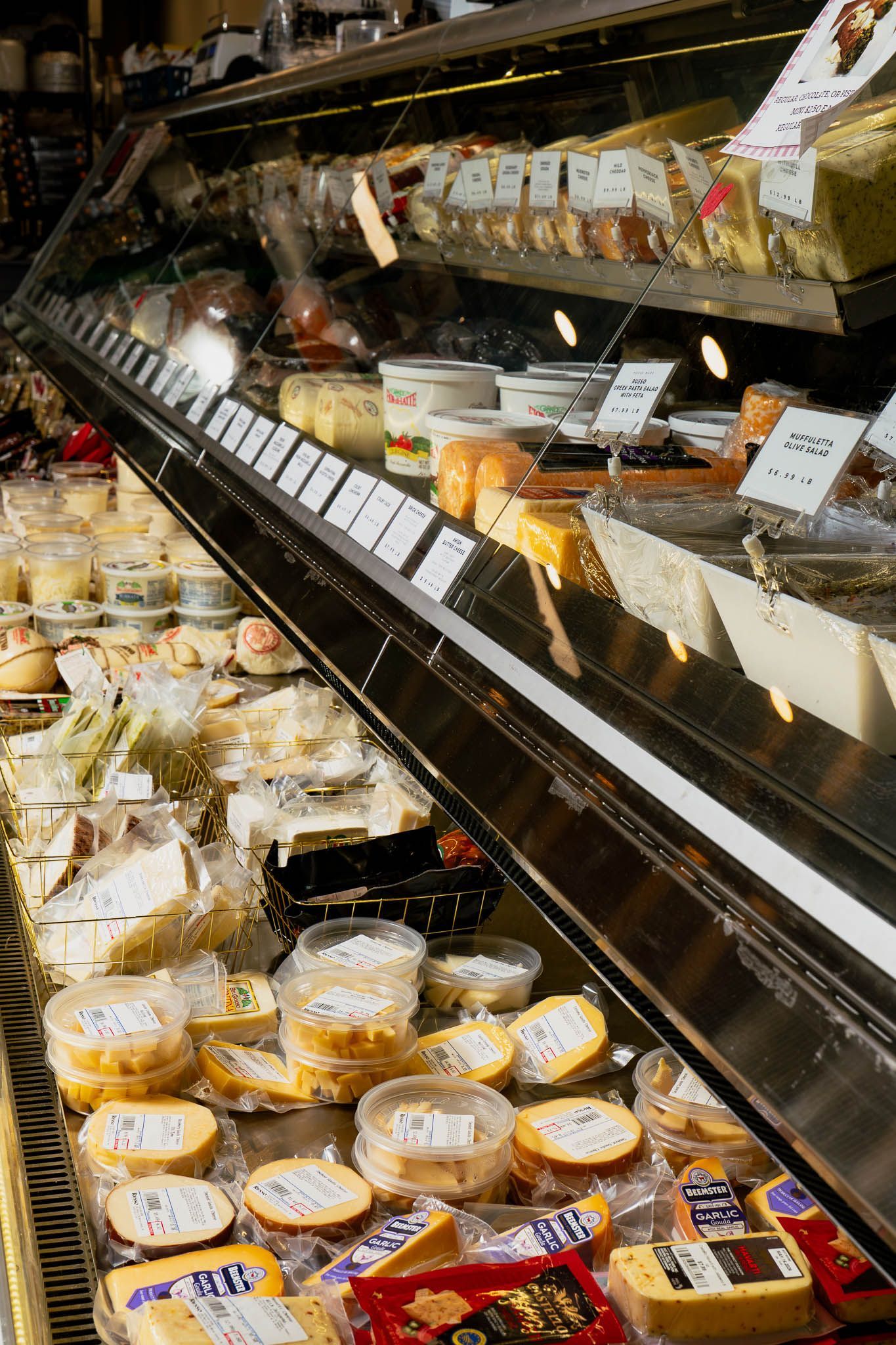 Display case of various prepared foods, including nuts, vegetables, and cheeses.