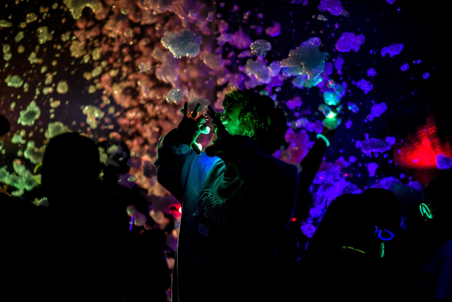 People in a dark room surrounded by colorful foam, illuminated by neon lights.