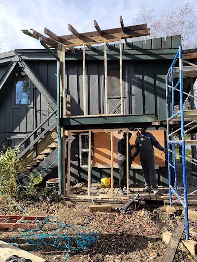A man is standing on a scaffolding next to a house under construction.