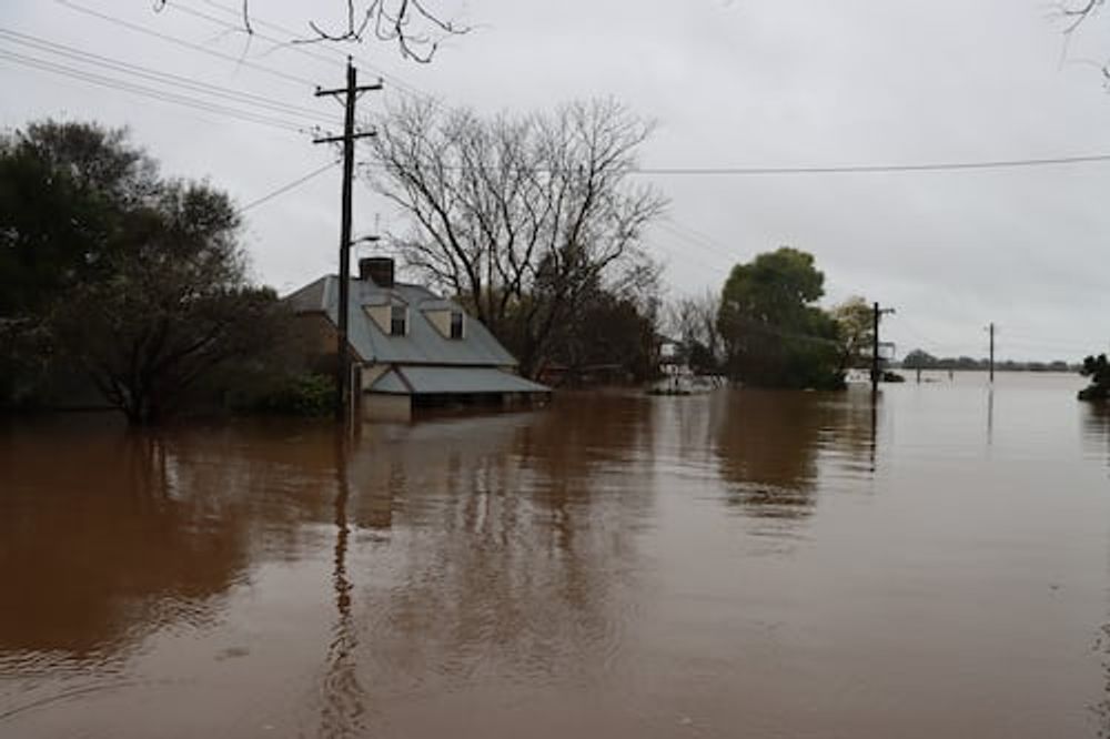 A house is surrounded by flood water in a flooded area.