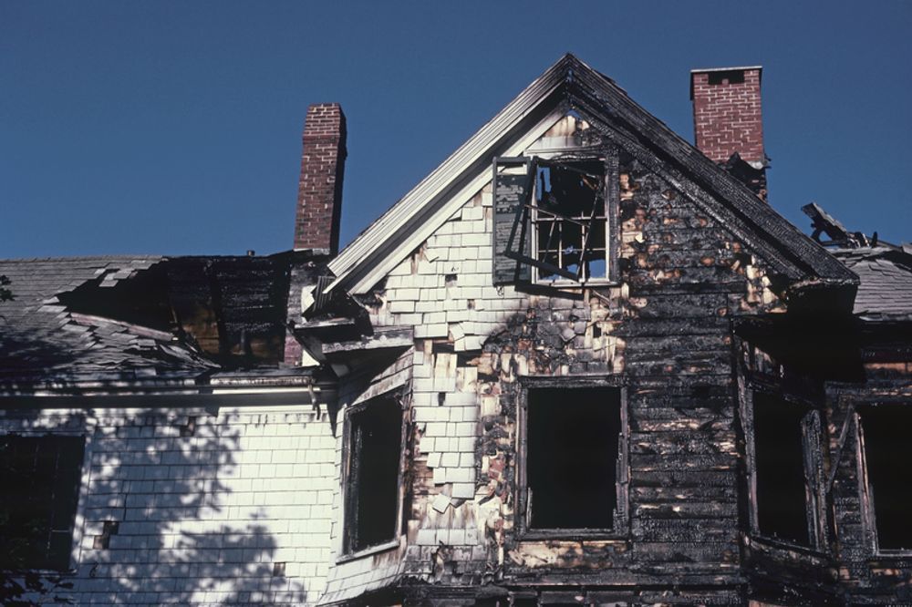 An old abandoned house with a chimney and a blue sky in the background