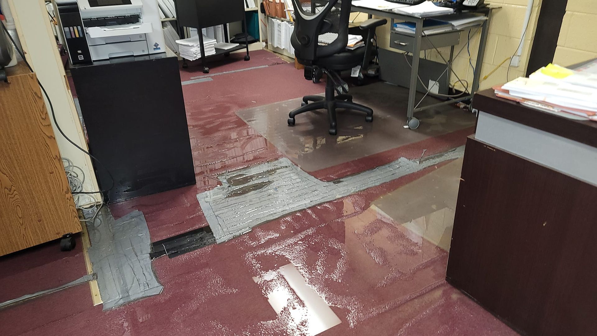 A flooded office with a desk , chair , and printer.