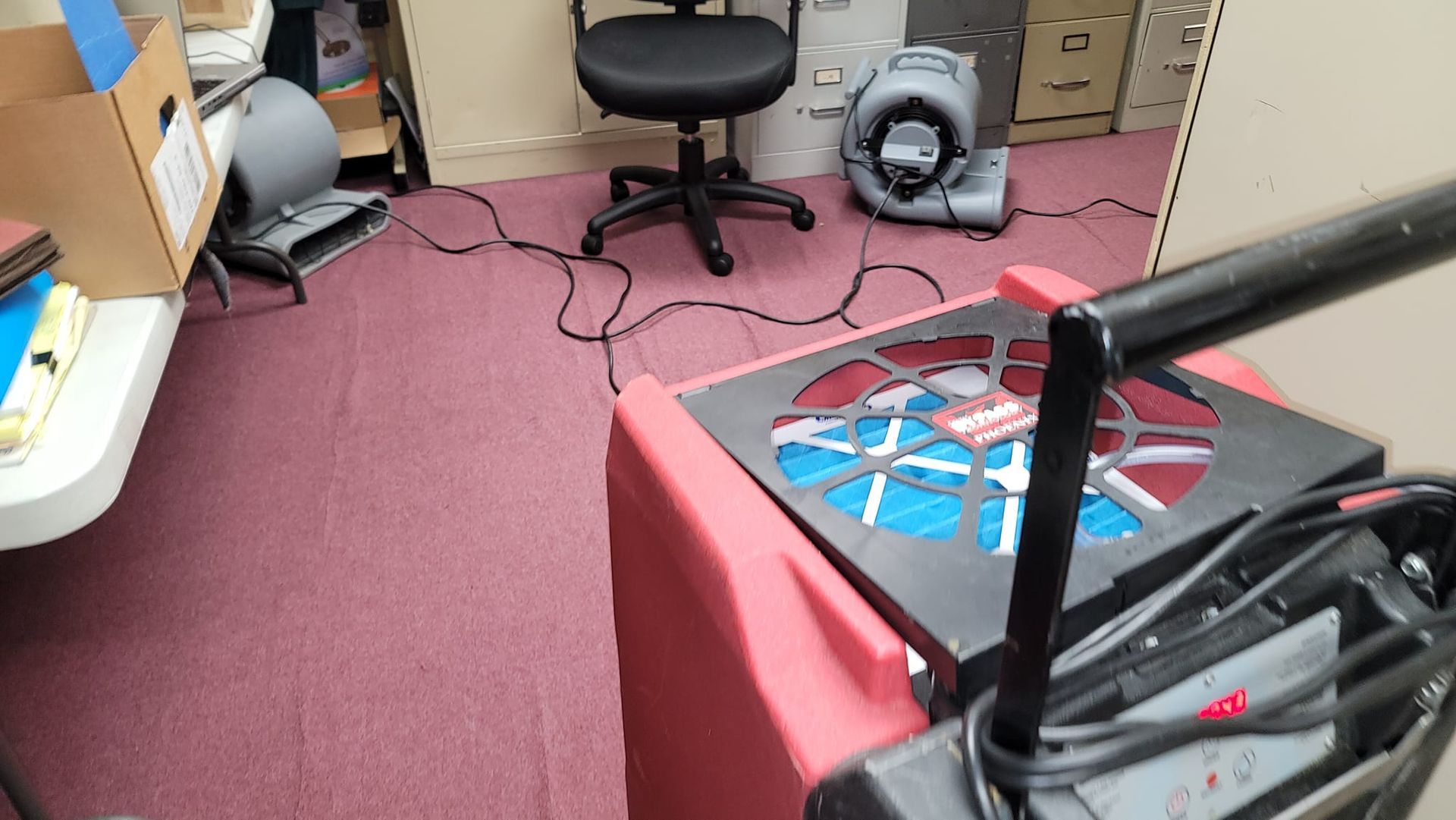 A room with a chair and a fan on the floor.