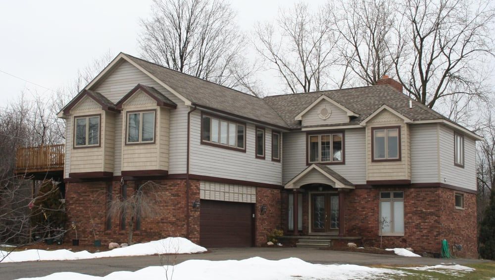 A large house with snow on the ground and trees in the background