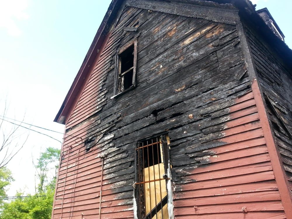 An old wooden house with a broken window and a fence around it