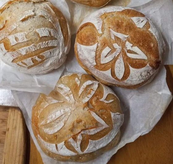 Four loaves of bread are sitting on a piece of wax paper