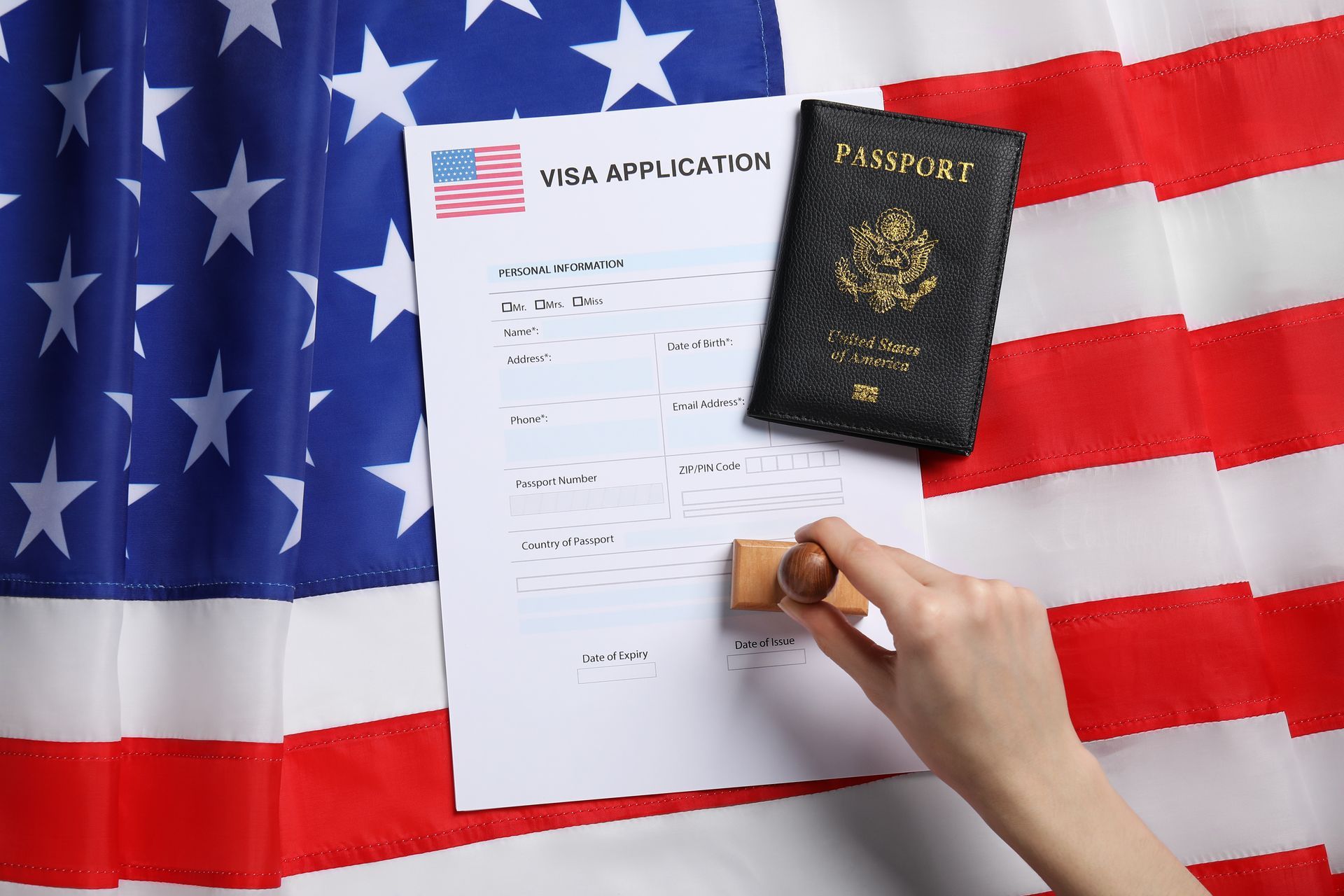 Hand stamping a visa application and passport on a US flag.