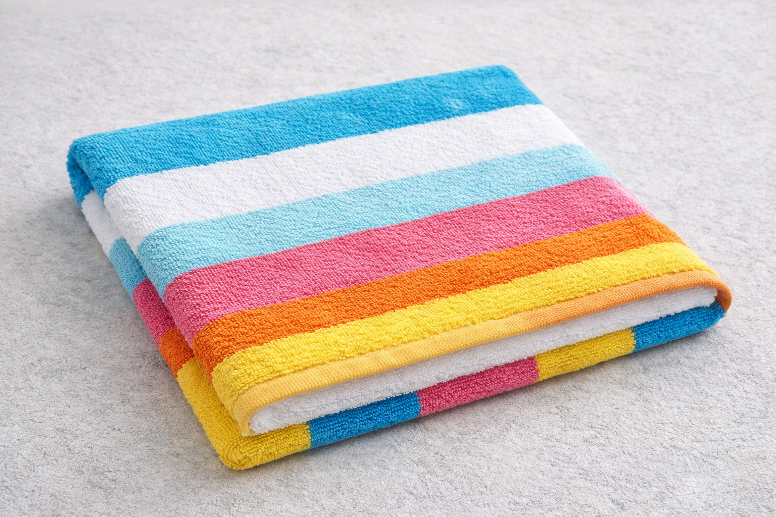 Folded, striped beach towel with blue, white, pink, orange, and yellow bands, on a light grey surface.