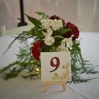 Table centerpiece with red and white flowers and a card marked “9” on a white tablecloth