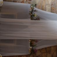 Sheer white fabric draped over a floral arrangement on a stone floor and patterned wall