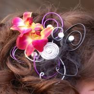 Close-up of curly hair with pink-yellow flowers and a purple spiral hair accessory