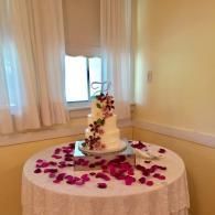 Wedding cake on a table covered with rose petals in a softly lit room
