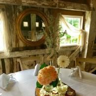 Rustic dining table with floral centerpiece in a wooden room by a window