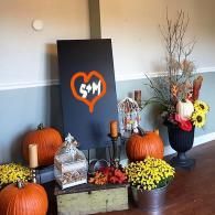 Fall Halloween display with pumpkins, yellow mums, lanterns, and a black board with orange heart sign