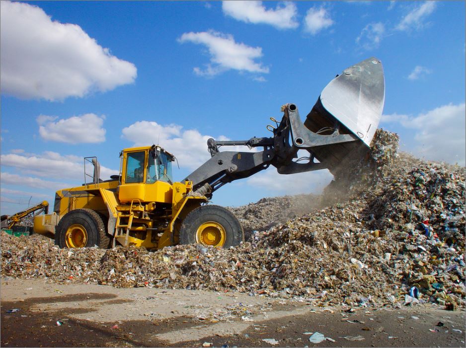 A digger clearing through landfill