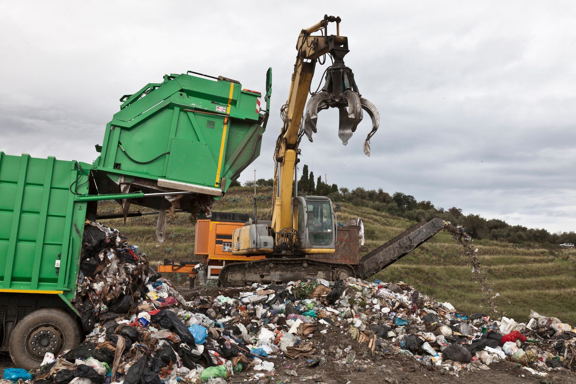 A crane and a dump truck disposing of landfill 