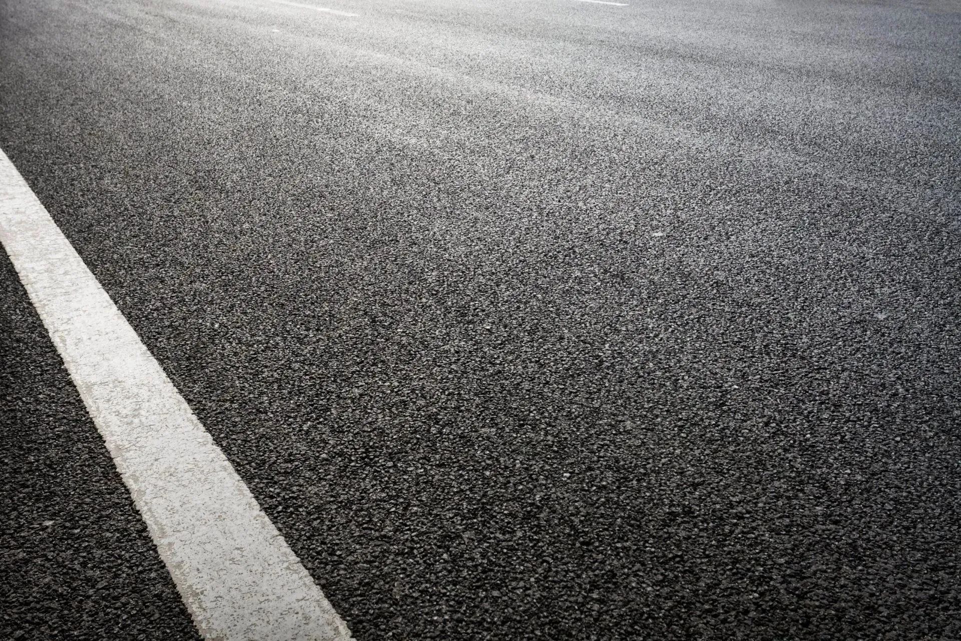 Close-up of a newly paved asphalt road with a white line marking
