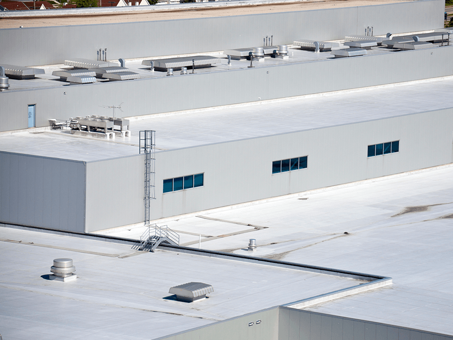 An aerial view of a large building with a white roof