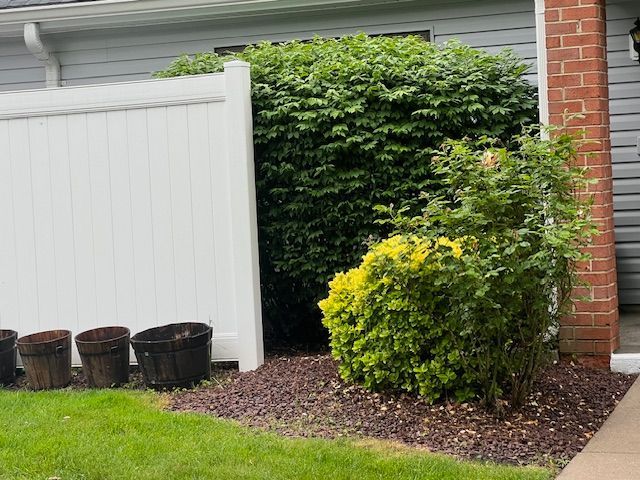 A white fence is in front of a brick house