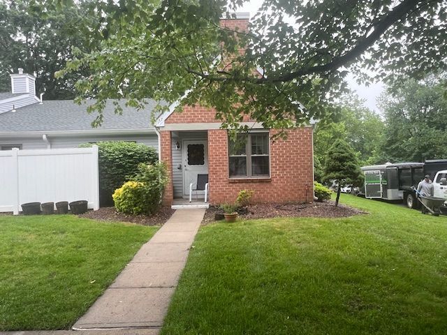 A small brick house with a white fence in front of it
