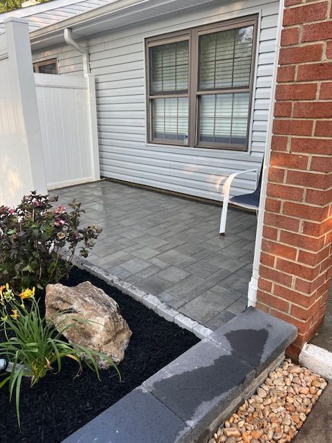 A brick house with a patio and a bench in front of it.