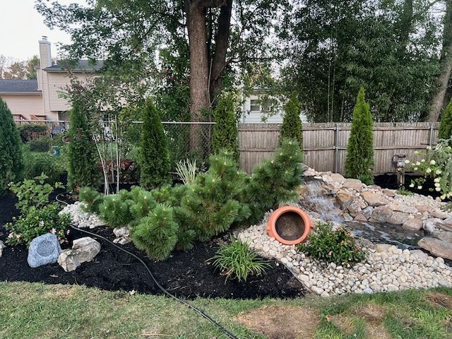 A backyard with a waterfall and a fence in the background.
