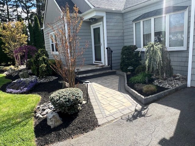 A gray house with a brick walkway leading to the front door.