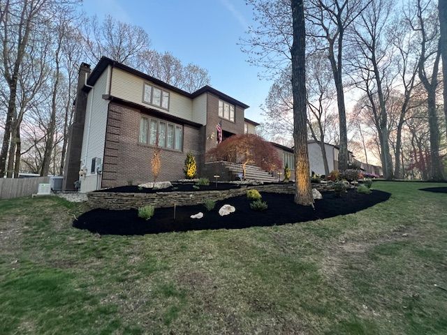 A large house is surrounded by trees and a lush green lawn.