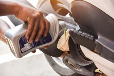 A person is pouring oil into a motorcycle engine.