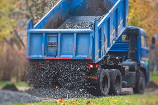 Blue dump truck unloading gravel stone