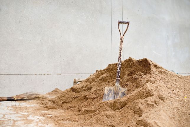 A pile of soil a shovel stuck in it