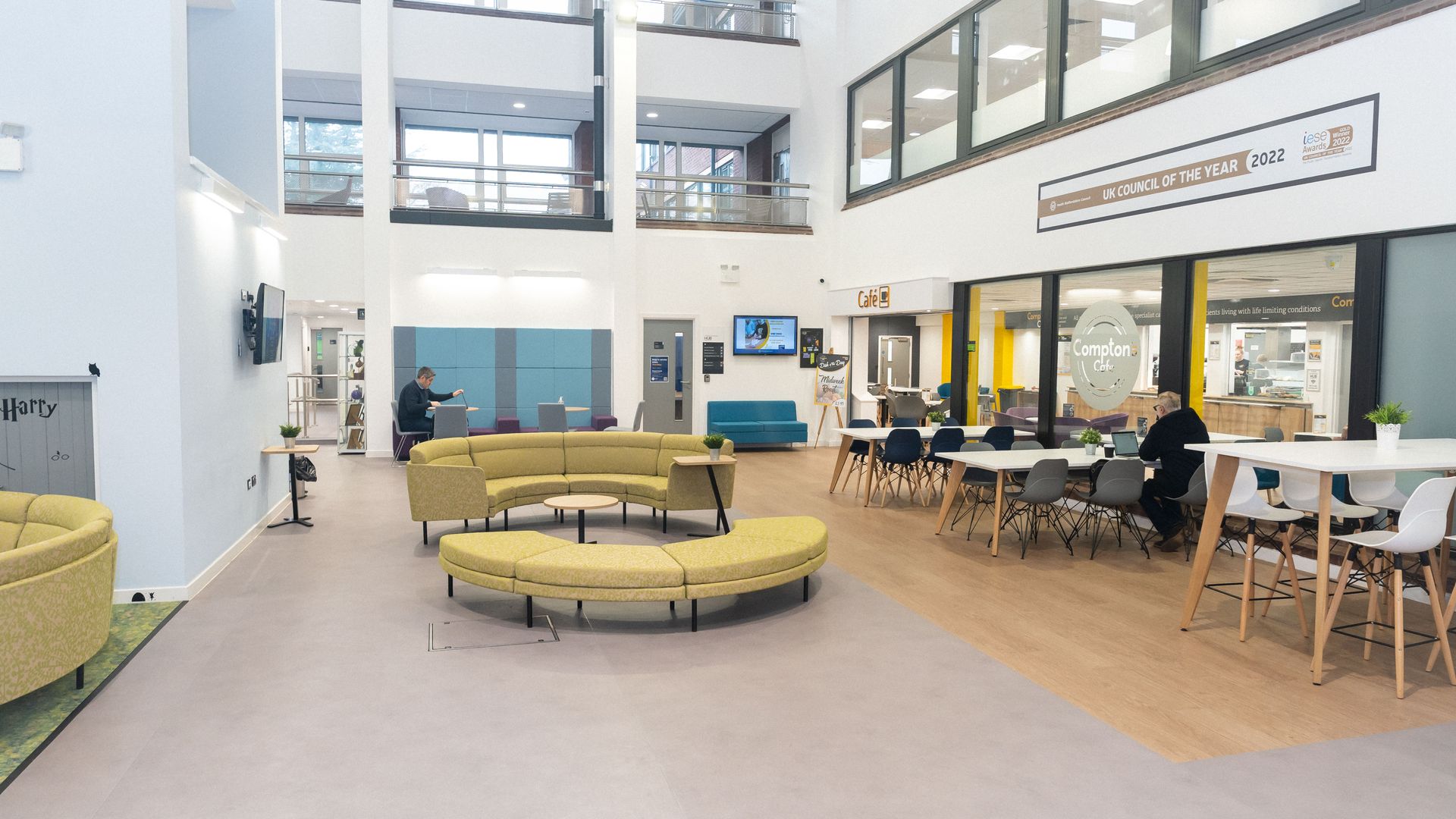 Spacious interior with seating areas, tables, and multiple floors. A person stands near a sofa.