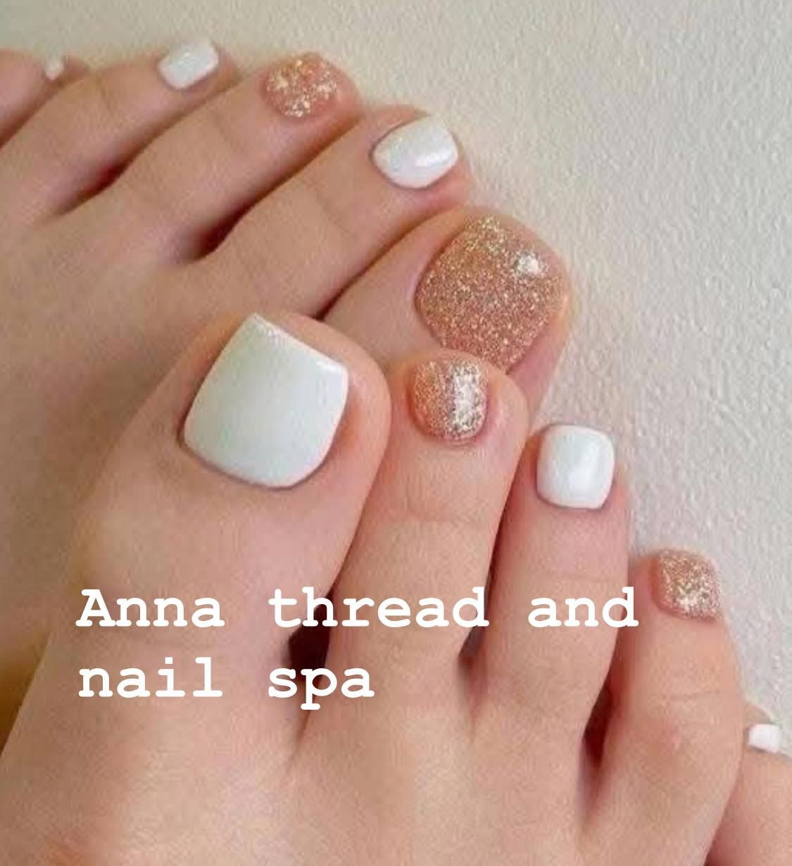 Pedicured feet with white and glittery gold nail polish, text: 