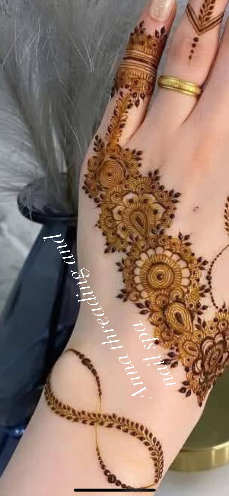 Henna hand art with intricate floral patterns and infinity symbol on a fair skinned hand.