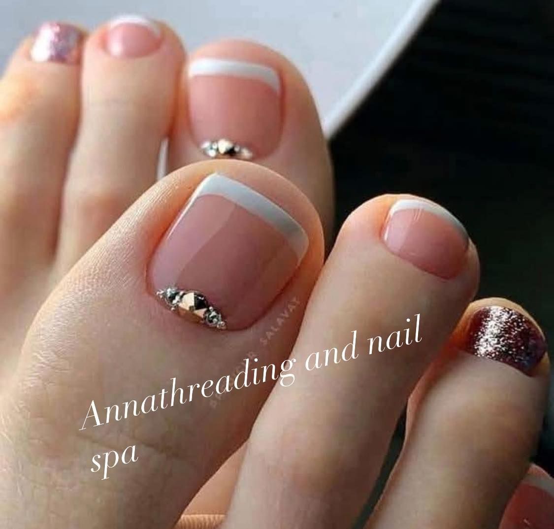 Close-up of a foot with a French pedicure; the big toe has a half-moon of rhinestones.