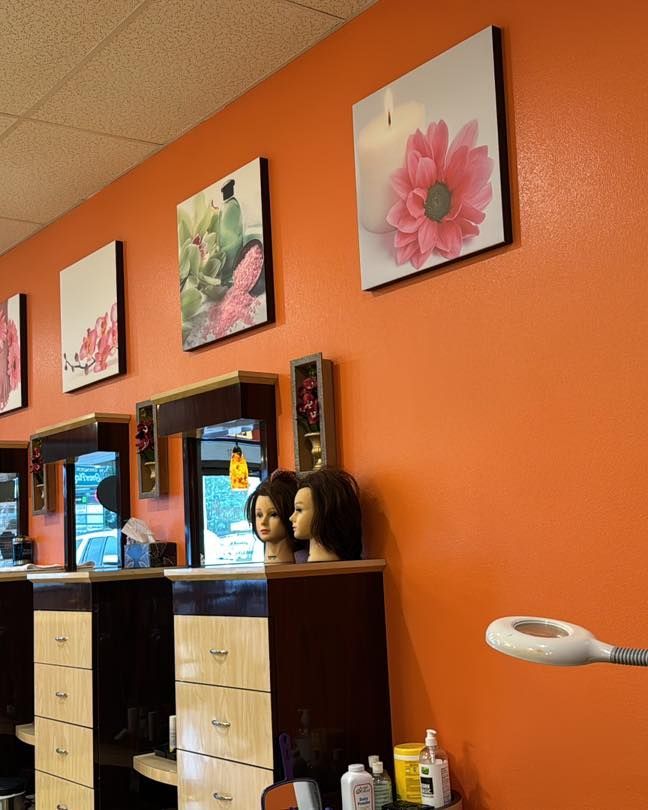 Hair salon interior with orange walls, flower art, mirrors, and styling stations.
