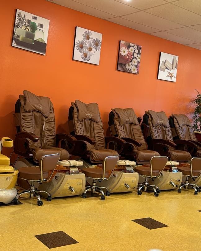 Pedicure chairs in nail salon with orange wall and floral art.