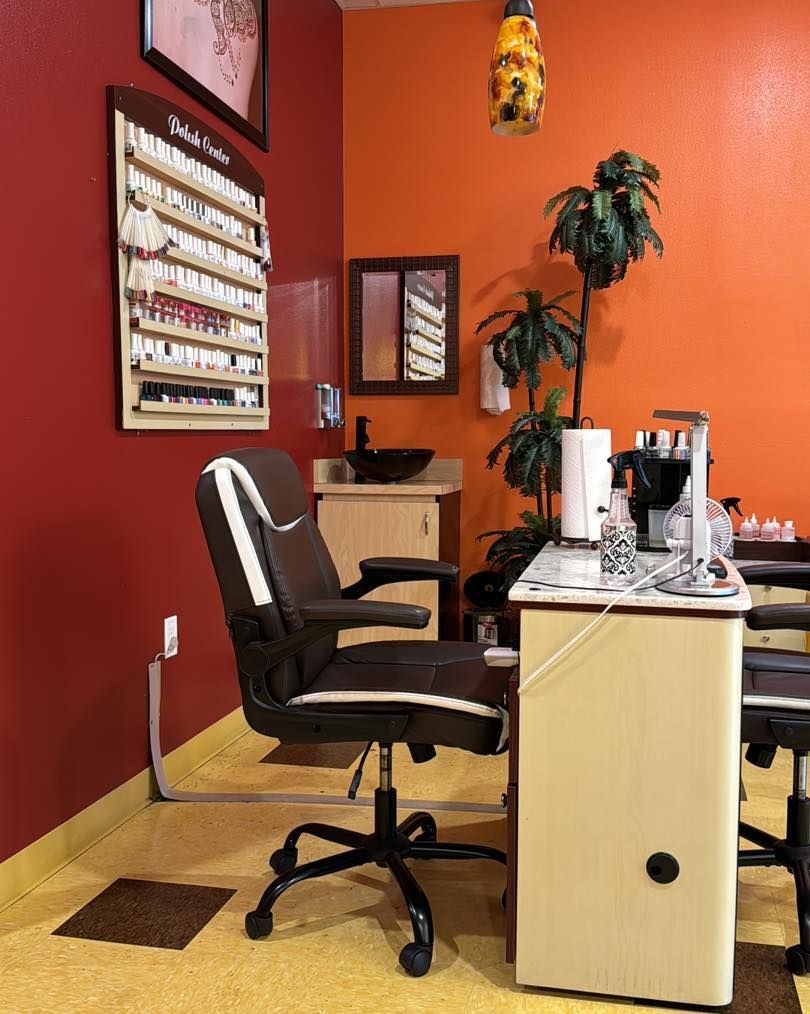 Nail salon corner with a chair, table, and nail polish samples. Orange and red walls, a plant, and a yellow floor.