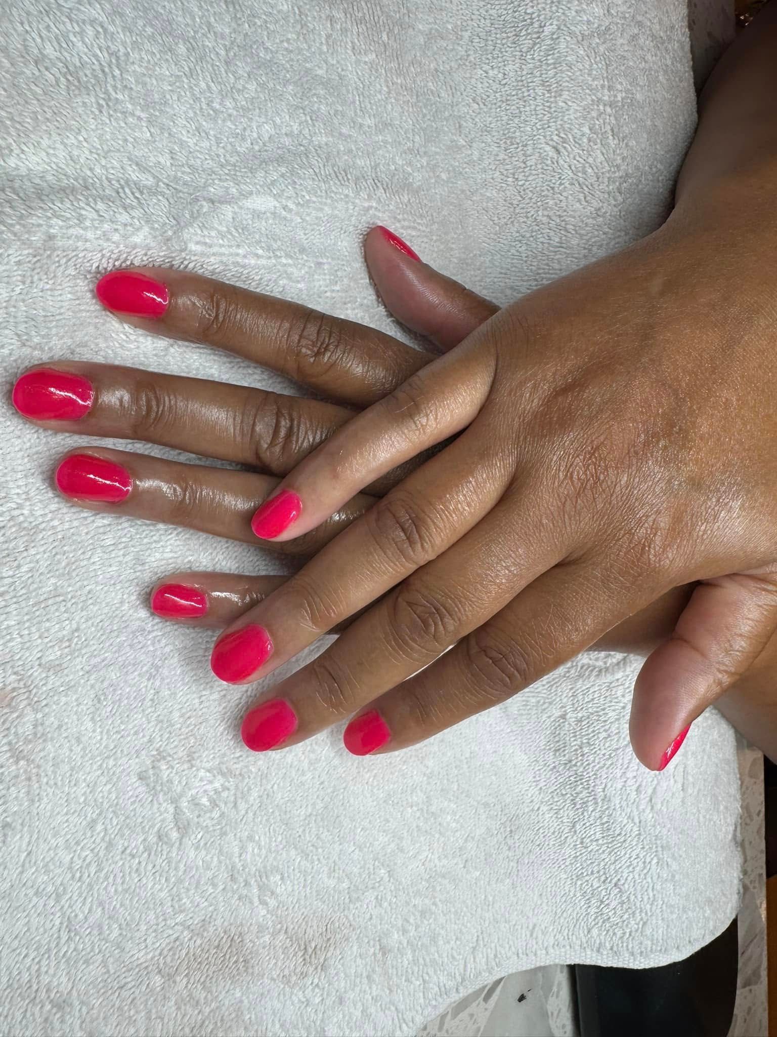 Hands with vibrant pink nail polish resting on a white towel.
