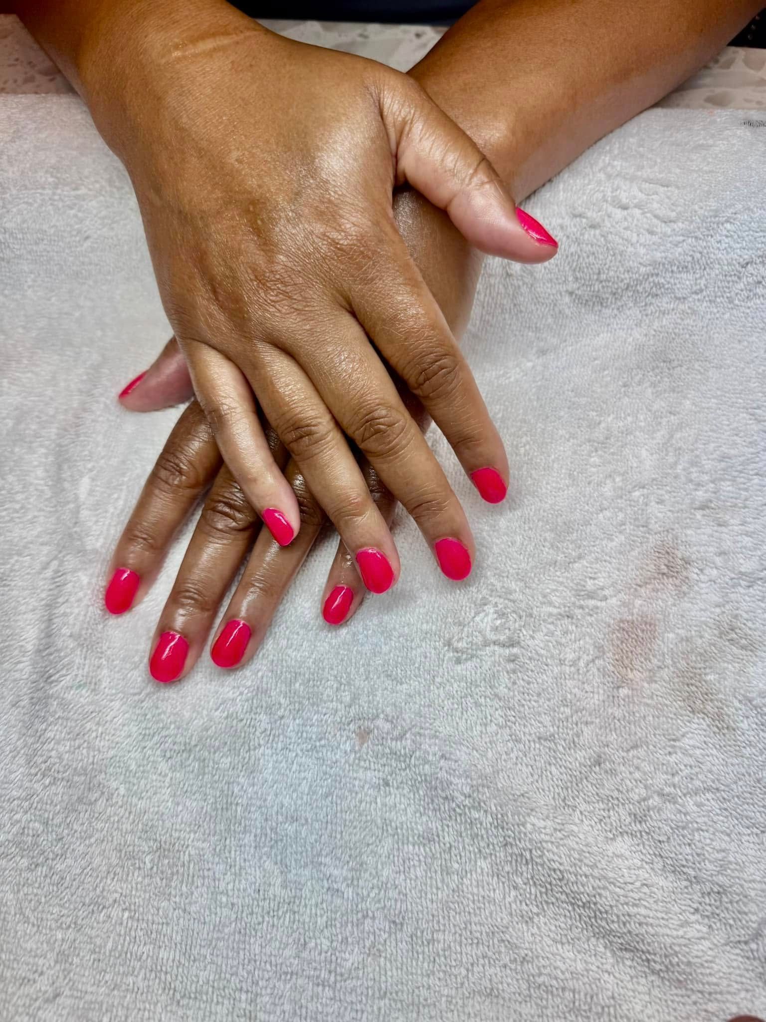 Hands with red nail polish resting on a white towel.