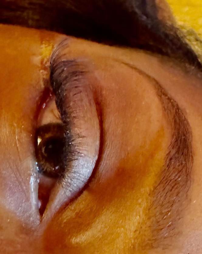 Close-up of a brown eye, eyebrow, and surrounding skin. Dark eyeliner and mascara are visible.