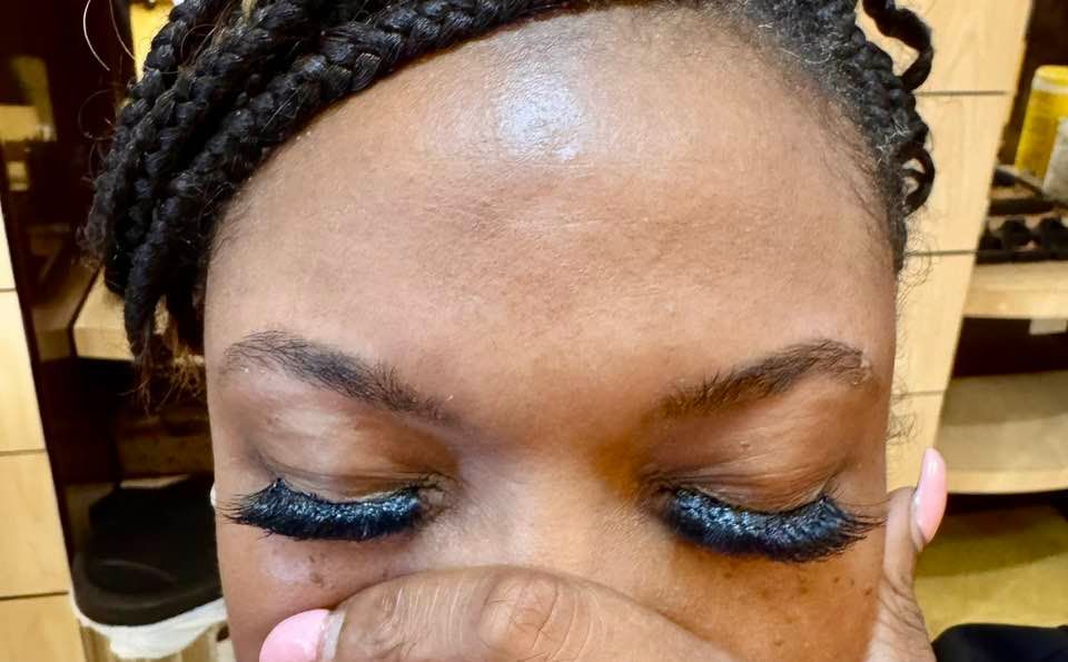 Woman with braided hair, closed eyes, and dark eyelashes. Hand near face.